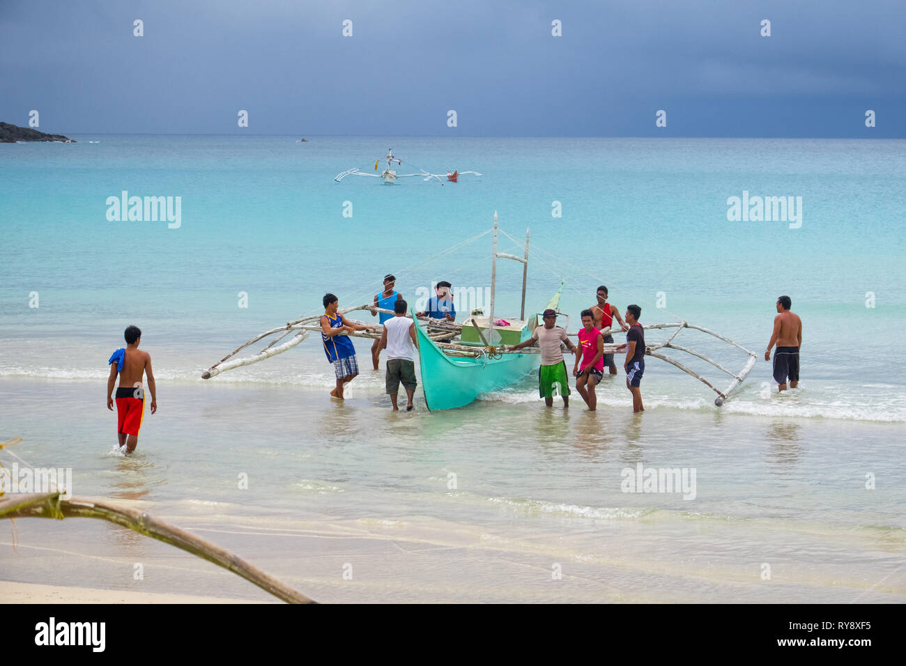 Diapila Beach, PALAWAN FILIPPINE - gli uomini nel villaggio di pescatori di portare un tour in barca per la spiaggia di Diapila, Palawan - Filippine Foto Stock