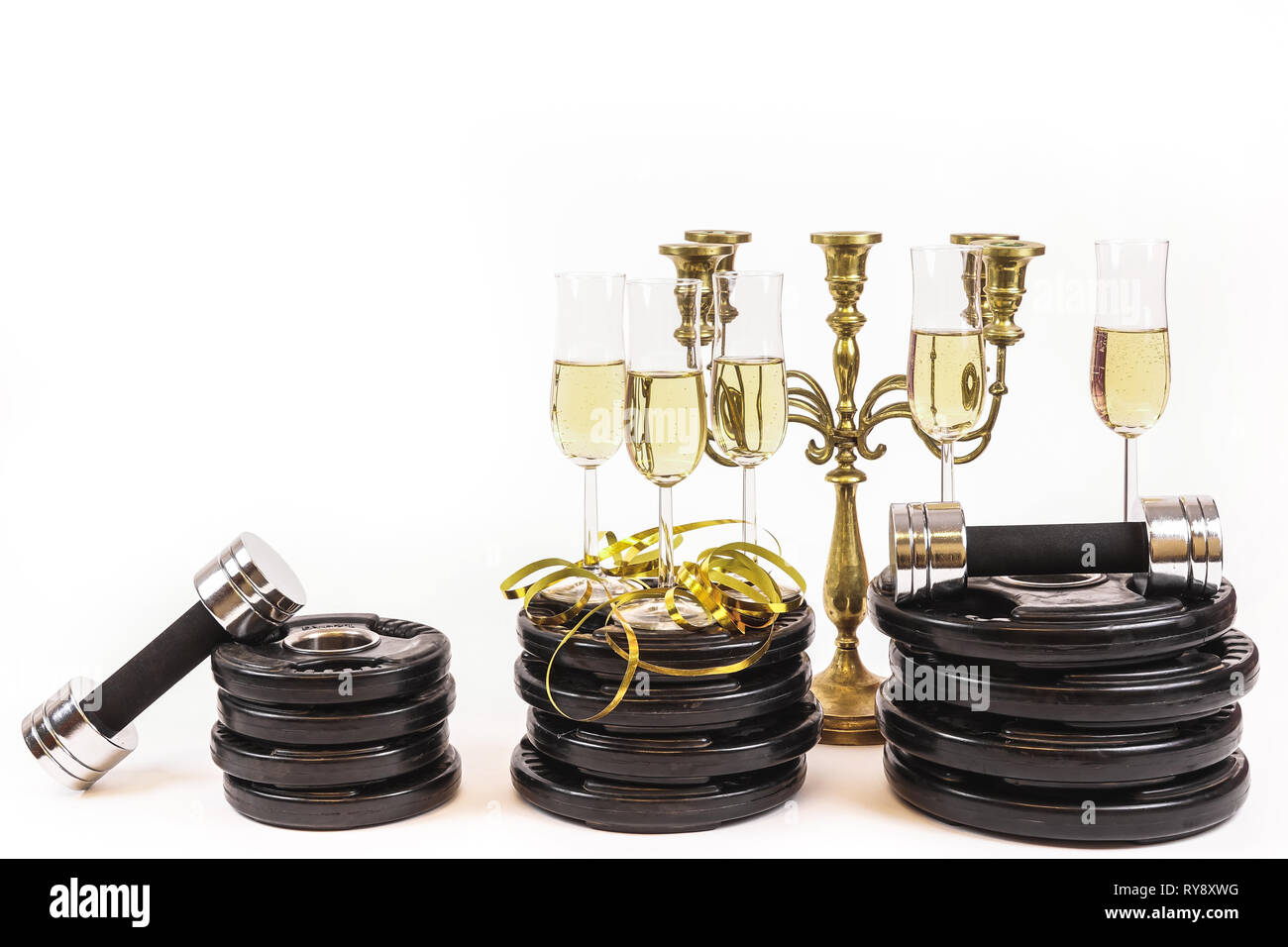 Nuovo anno risoluzione. Festeggiare il capodanno in palestra. Bicchieri di champagne su piastre di peso e manubri. Allenamento ed esercizio di più l'anno prossimo. Emp Foto Stock