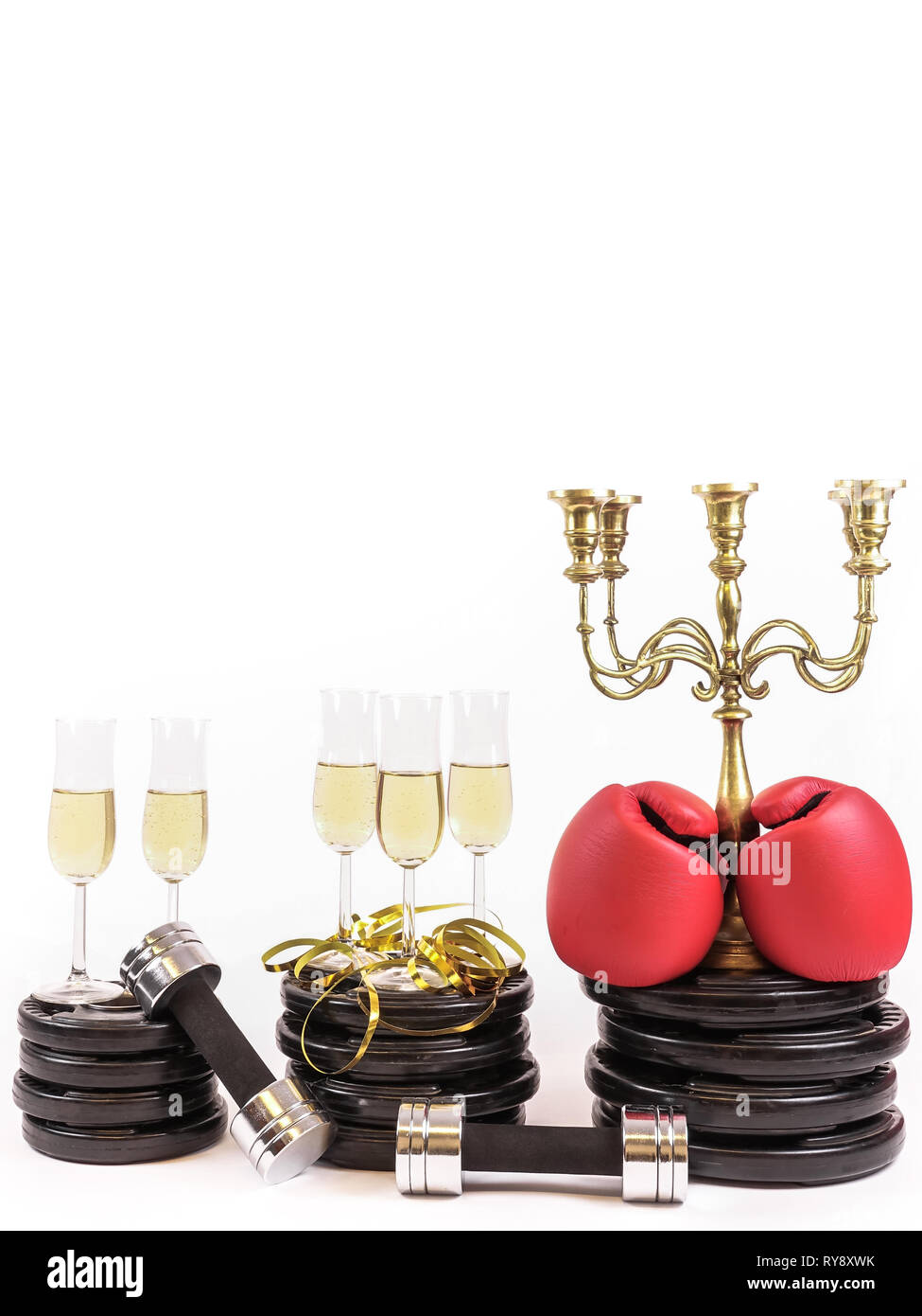 Nuovo anno risoluzione. Festeggiare il capodanno in palestra. Bicchieri di champagne su piastre di peso e manubri. I guantoni candelabri. Allenamento e Foto Stock