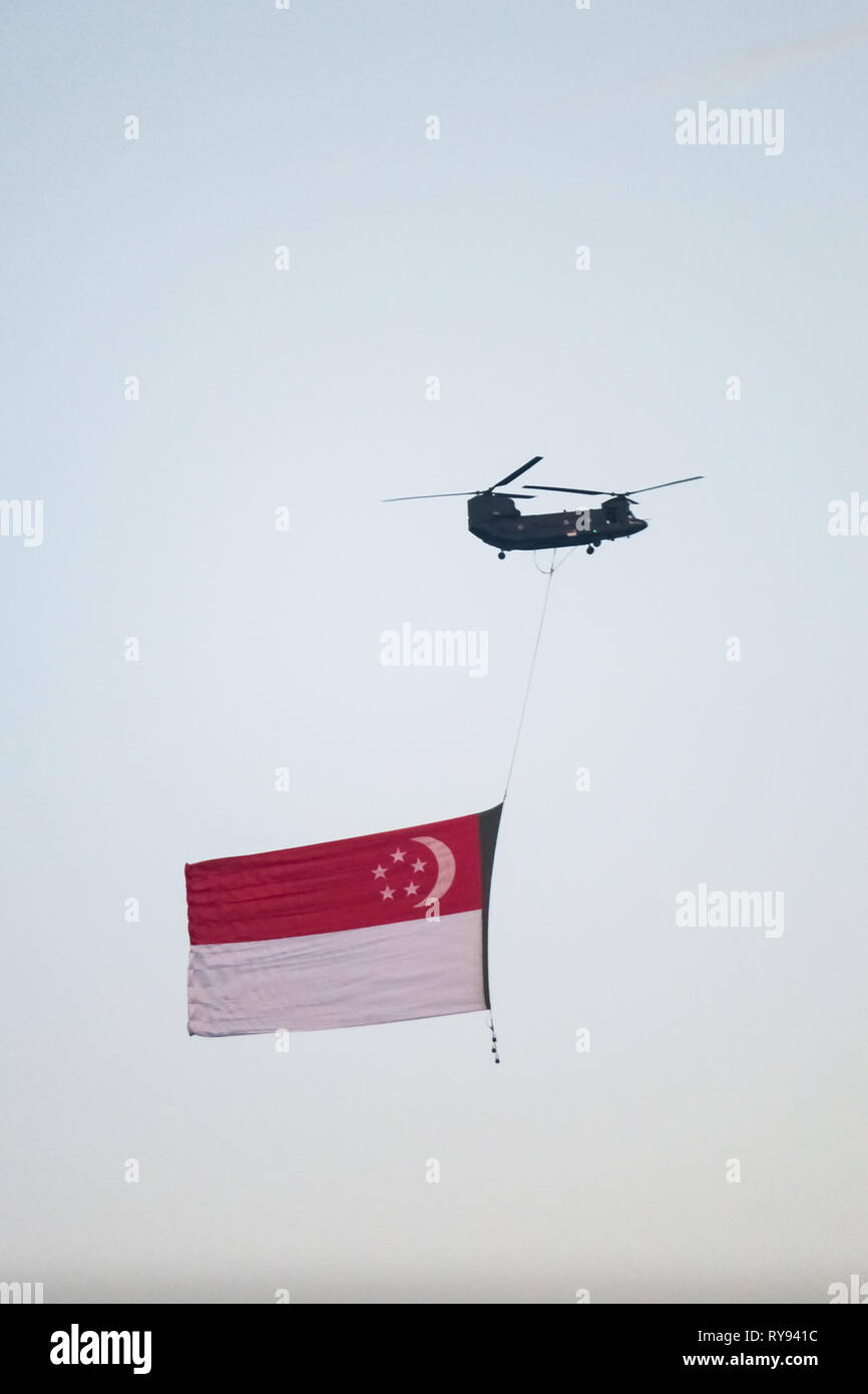 CH-47 Chinook elicottero militare portando una grande bandiera di Singapore. Il Marina Bay, Singapore Foto Stock