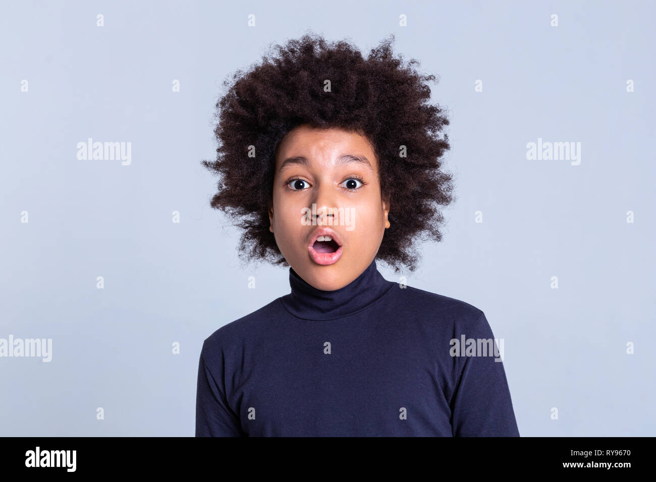 Dark-dai capelli ricci capretto piccolo essere rimasto scioccato e aprire la bocca Foto Stock