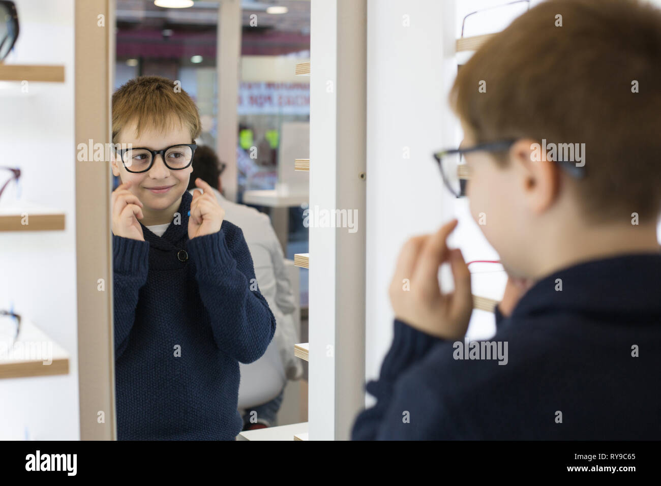 Carino giovane ragazzo cercando sui bicchieri in un negozio di occhiali Foto Stock