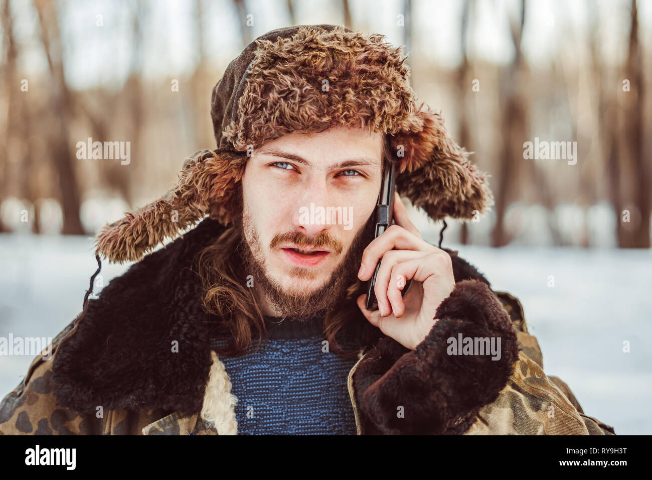 Siberiano uomo russo in un cappello con cuffie e telefono Foto stock - Alamy