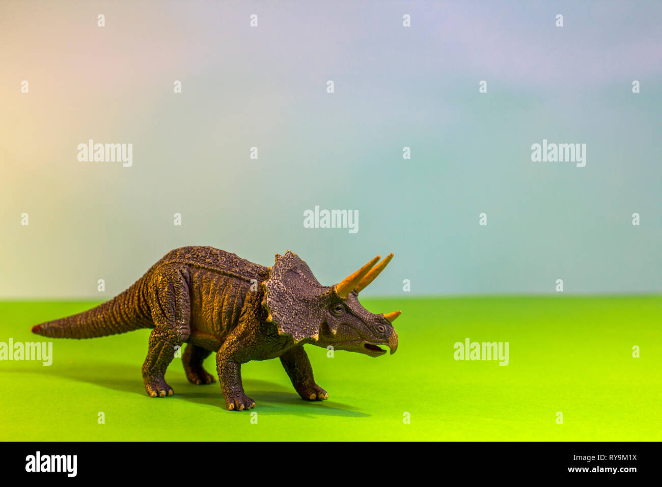 Dinosauro giocattolo in una foresta giocattolo. come un vero e proprio dino su uno studio luminoso dello sfondo con alberi di legno. Eco giocattoli. Foto Stock