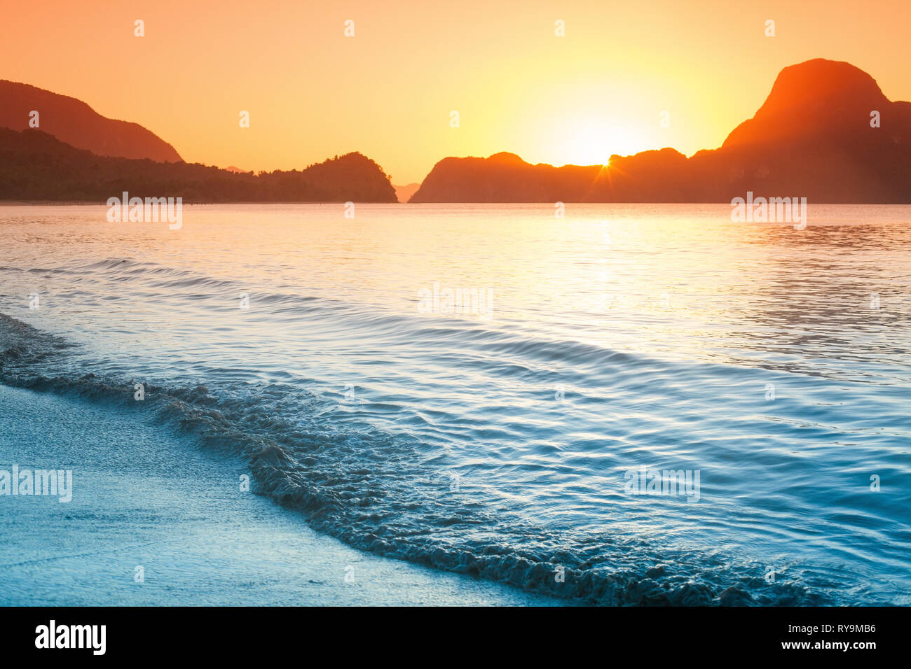Colorato tramonto su una spiaggia con rocce Foto Stock