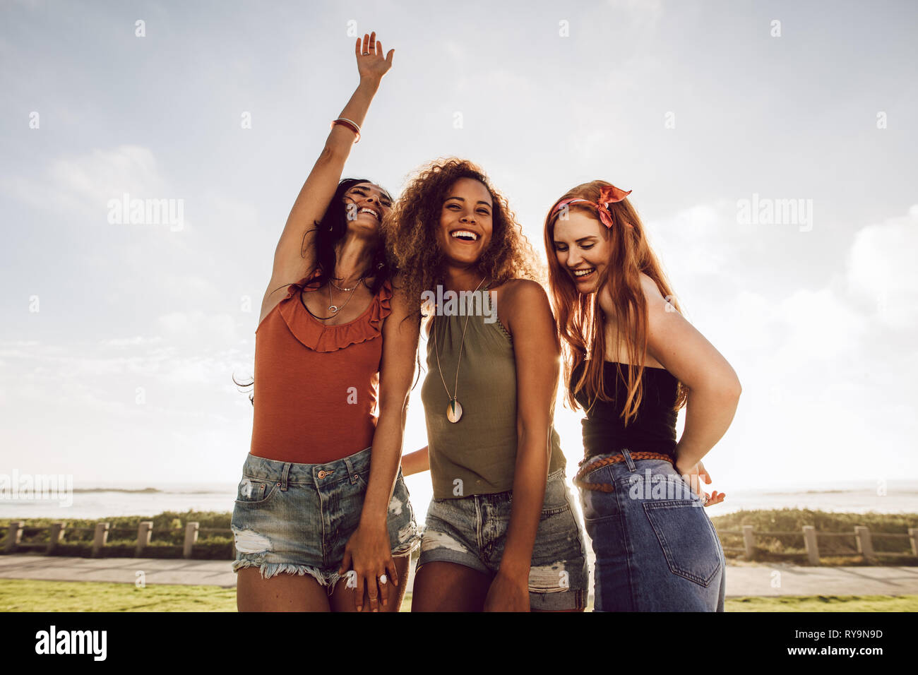 Un gruppo di tre giovani donne in piedi all'aperto e balli. Bella amici di sesso femminile avente un grande tempo sulle loro vacanze estive. Foto Stock