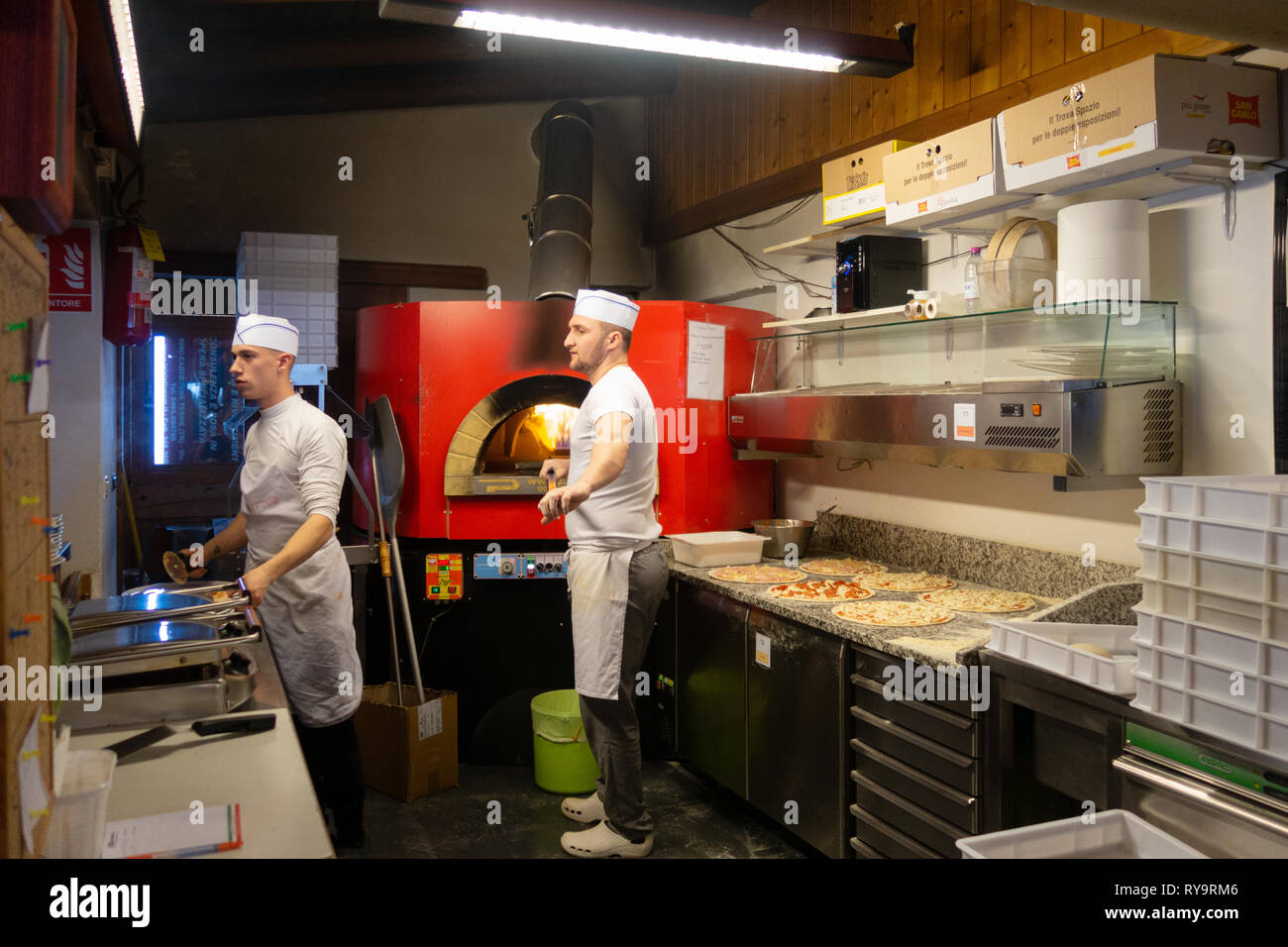 Italia Pizza cuochi; le persone che lavorano per la cottura della pizza in un ristorante pizzeria, Caderzone village, Dolomiti Italia Europa Foto Stock
