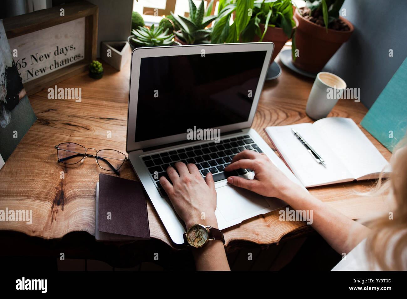 Una ragazza in un bar con un portatile funziona in un luogo accogliente con una tazza di caffè, prende piacere. Il concetto di freelancing Foto Stock