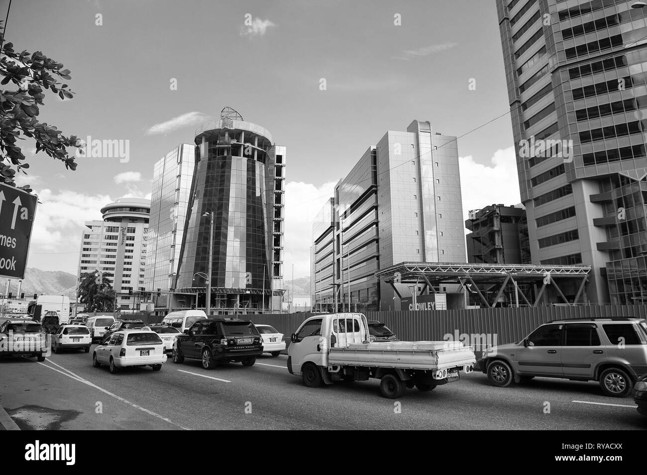 Porto di Spagna, Trinidad e Tobago - Novembre 28, 2015: city road con i trasporti e gli edifici moderni con facciata di vetro in città sul cielo blu sulle strade Foto Stock