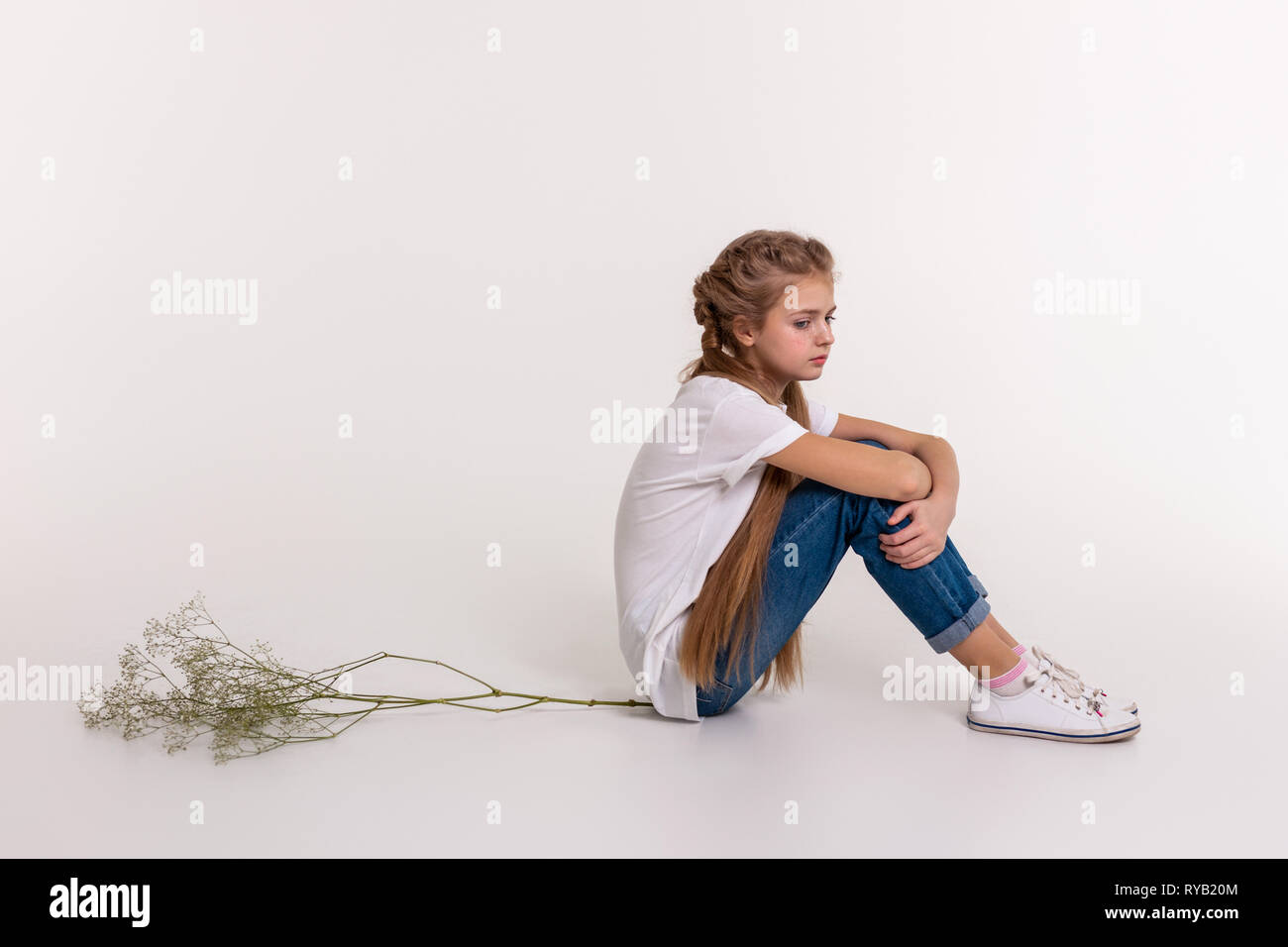 Sconvolto ragazza giovane con estremamente lunghi capelli seduto in posizione chiusa Foto Stock