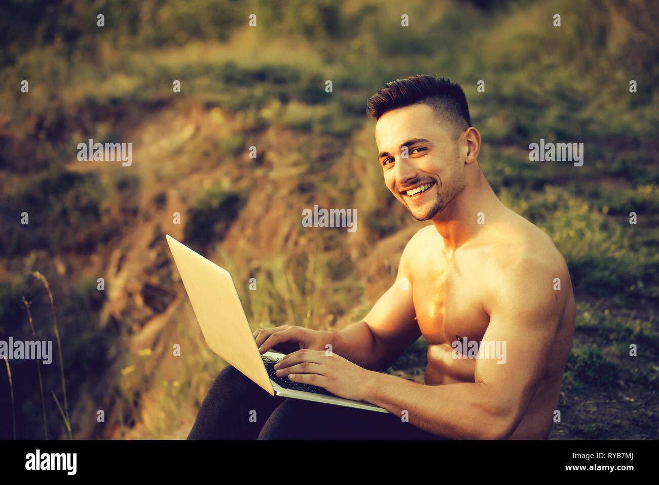Sorridente uomo muscolare con il computer portatile per esterno Foto Stock