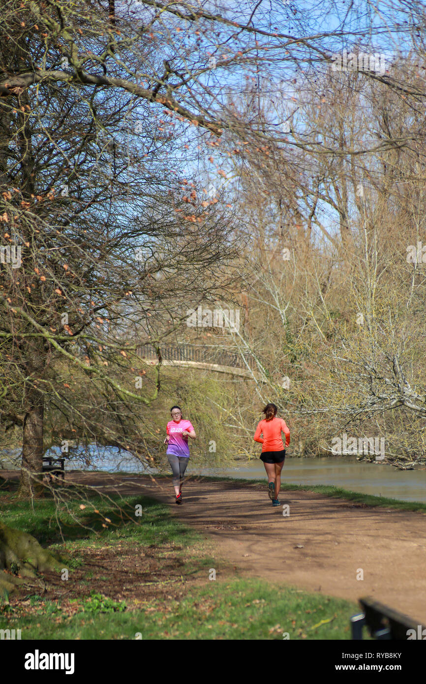 Due guide femmina sul sentiero di ghiaia Lazenbee il suolo a piedi dal fiume Cherwell Oxford University parchi del sole in inverno / molla Foto Stock