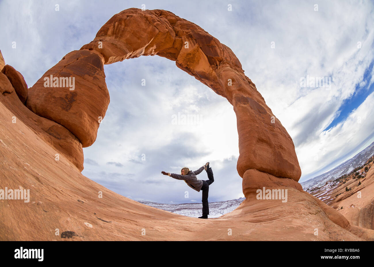 Escursionista facendo un bilanciamento di yoga pone alla base di Delicate Arch Foto Stock