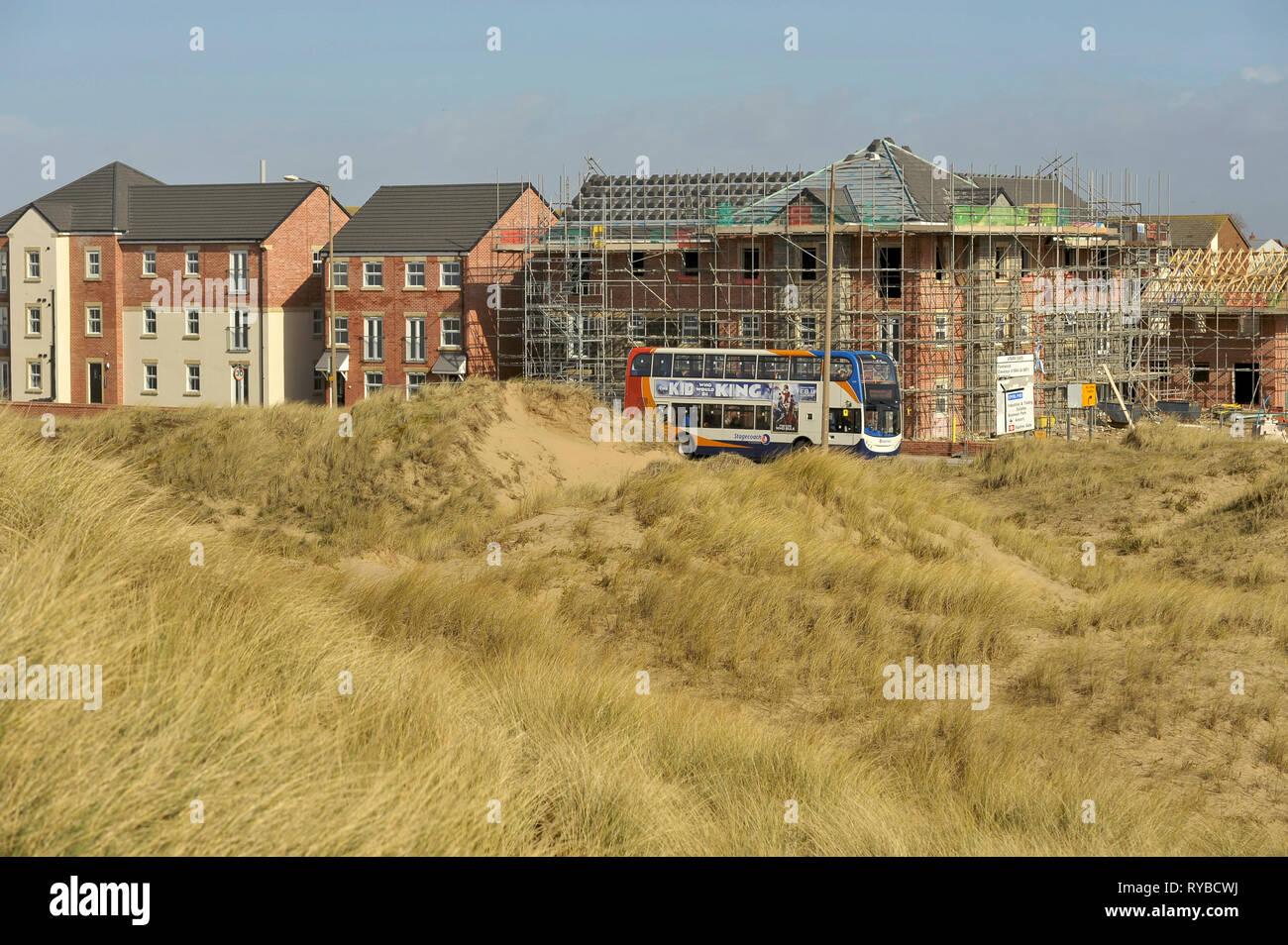 Stagecoach bus passando house edificio progetto andando su opposti protetti dune di sabbia sulla costa di Lancashire Foto Stock