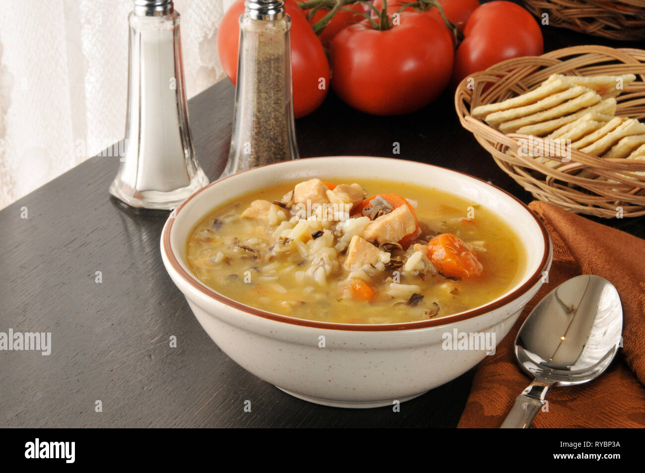 Una ciotola di zuppa di pollo con riso selvatico e saltilne cracker Foto Stock