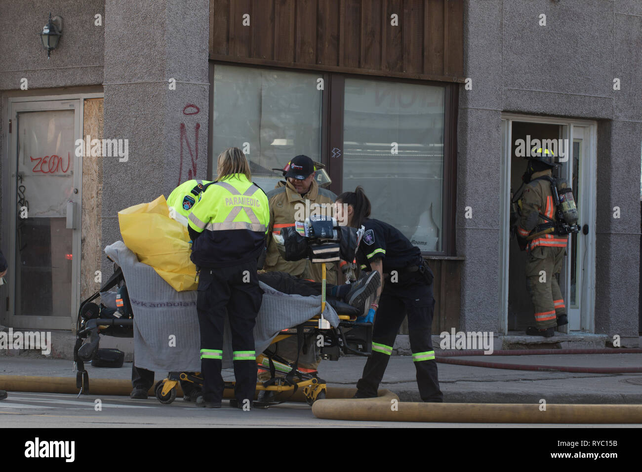 Hamilton, Canada 2019: ambulanza paramedici aiutare le vittime di inalazione di fumo causato da un grande costruire FIRE. Sicurezza e soccorso dei lavoratori durante un Foto Stock