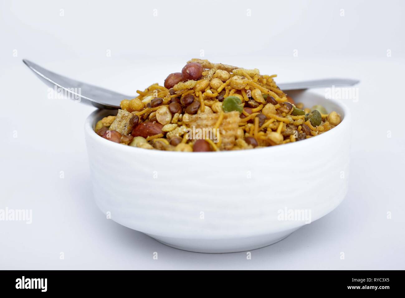 Foto di mix namkeen con il cucchiaio nella ciotola. Isolato su uno sfondo bianco. Foto Stock
