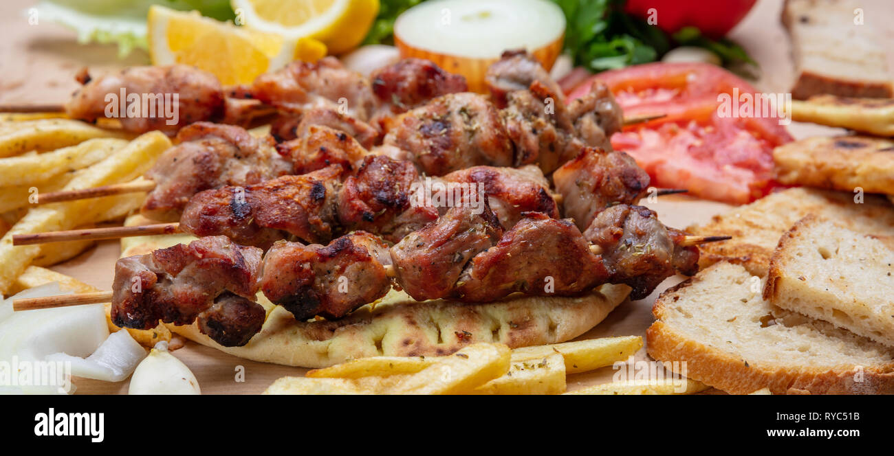 Souvlaki, spiedini di carne e quella greca tradizionale turco alimenti a base di carne sul pane pita,verdure e patate, banner Foto Stock