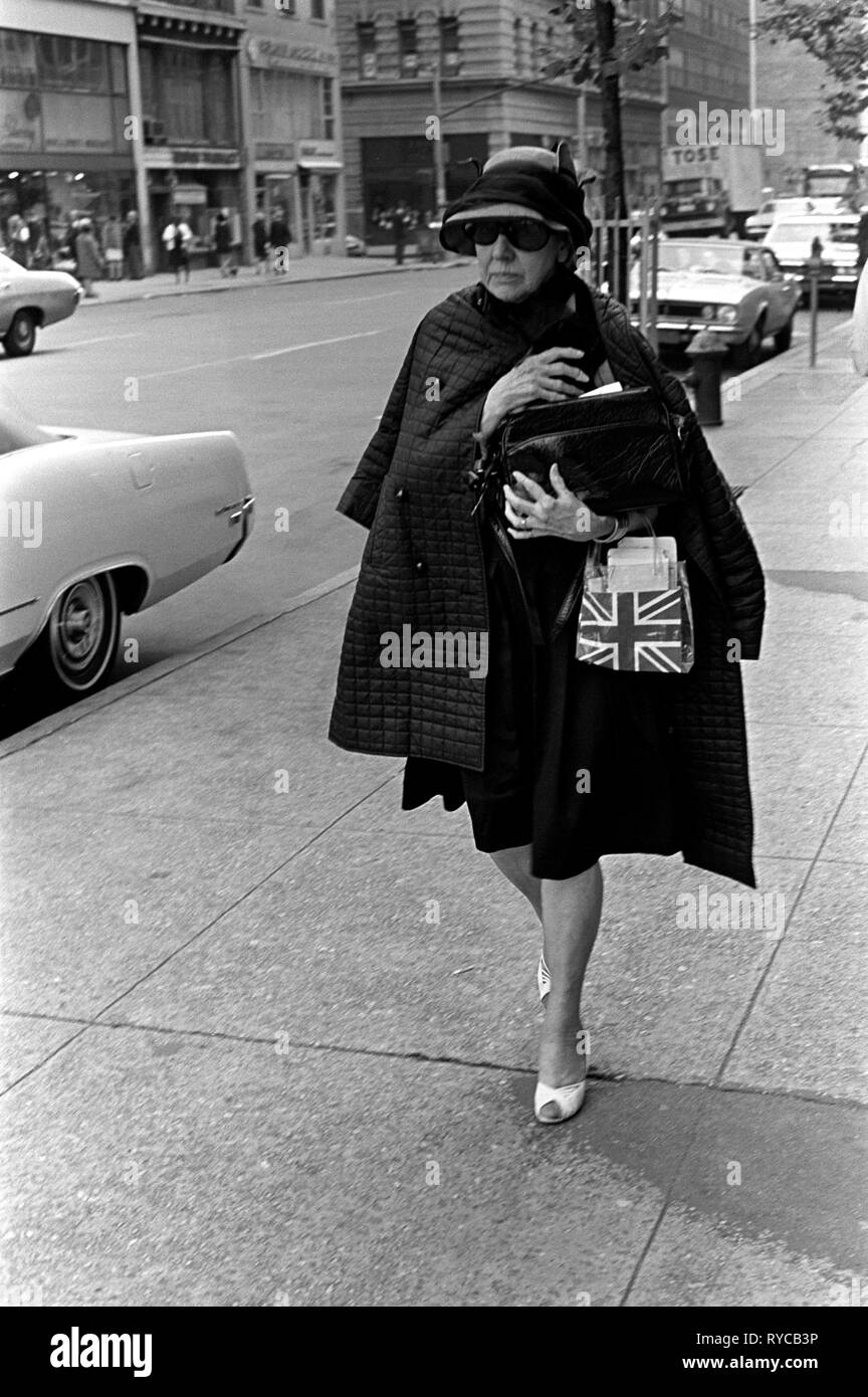 Manhattan street scene degli anni sessanta la moda più anziani vestiti alla moda donna porta una bandiera dell'Union Jack borsa a mano come ella si appresta a un appuntamento. 1969 60s USA US HOMER SYKES Foto Stock