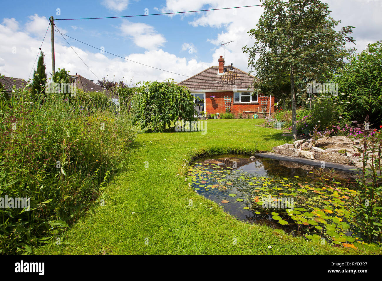 Giardino urbano con laghetto prato alberi e bungalow Ringwood Hampshire REGNO UNITO Inghilterra Giugno 2016 Foto Stock