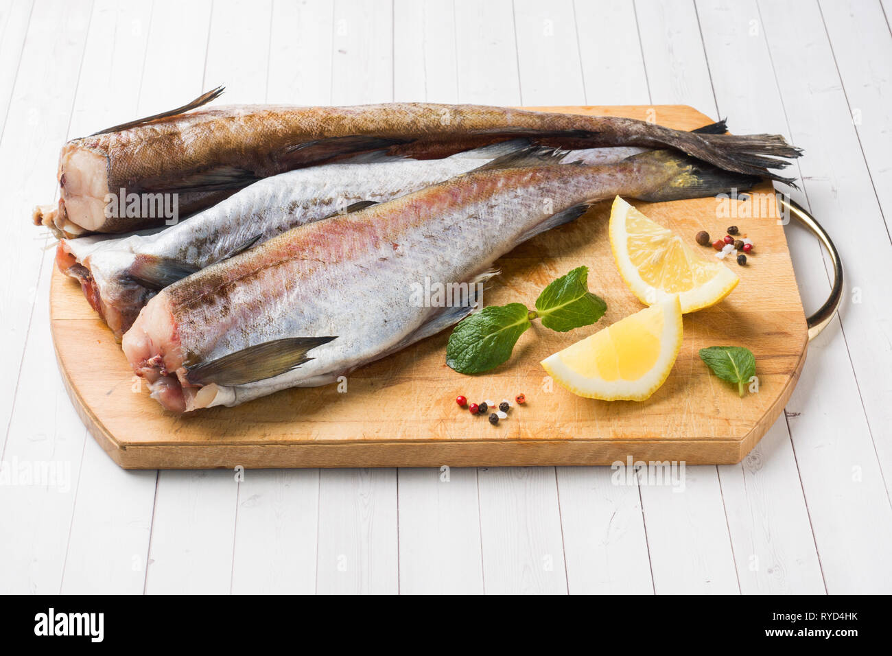 Crudo fresco di Pollock pesce su una tavola di legno con il limone. Foto Stock