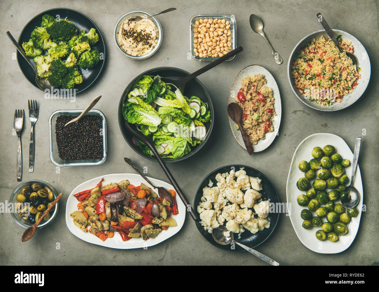 Vegane pranzo o cena messa in tavola. Varie sani piatti vegetariani in piatti e ciotole sul tavolo di calcestruzzo. Flat-lay di carni e verdure cotte s Foto Stock