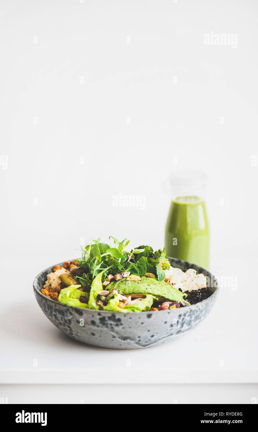 Una sana la cena o il pranzo. Vegan superbowl Buddha o ciotola con hummus, verdure, insalate fresche, fagioli, couscous e avocado e frullato verde in bottiglia Foto Stock