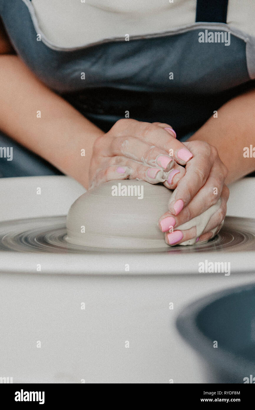 Creazione di un vaso o in un vaso di argilla bianca di close-up. Donna mani rendendo brocca di argilla su potter ruota. Foto Stock