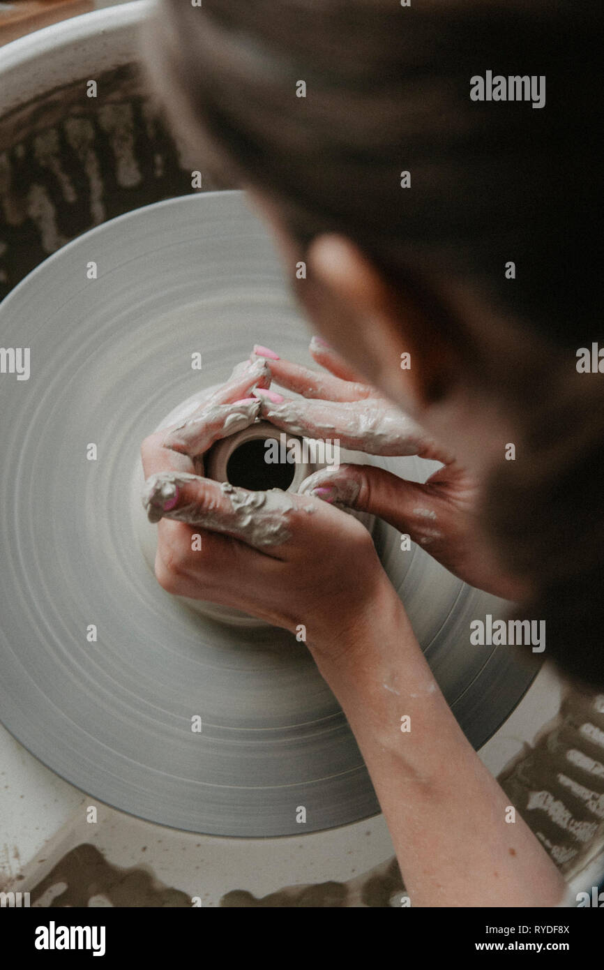 Creazione di un vaso o in un vaso di argilla bianca di close-up. Donna mani rendendo brocca di argilla su potter ruota. Foto Stock