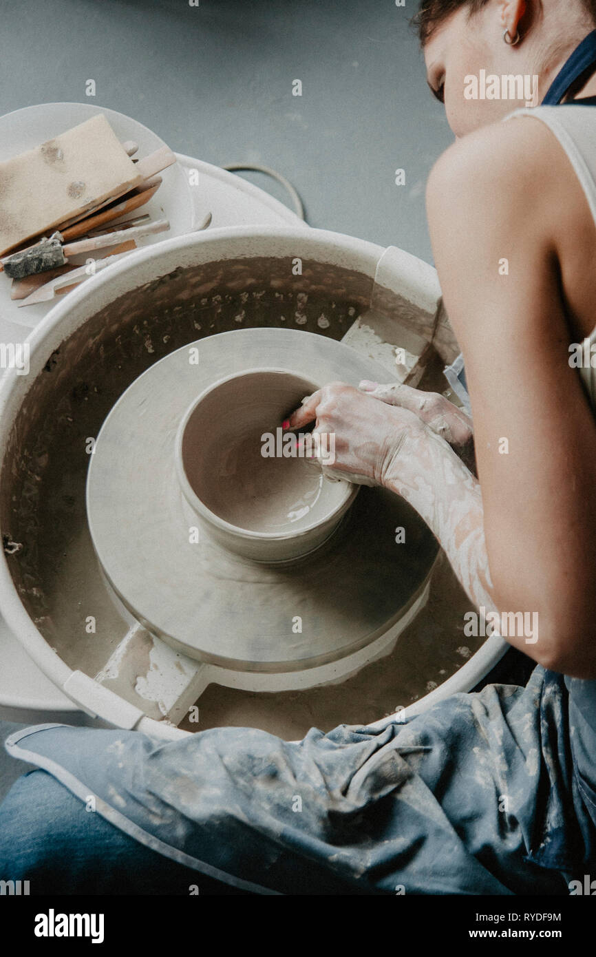Creazione di un vaso o in un vaso di argilla bianca di close-up. Donna mani rendendo brocca di argilla su potter ruota. Foto Stock