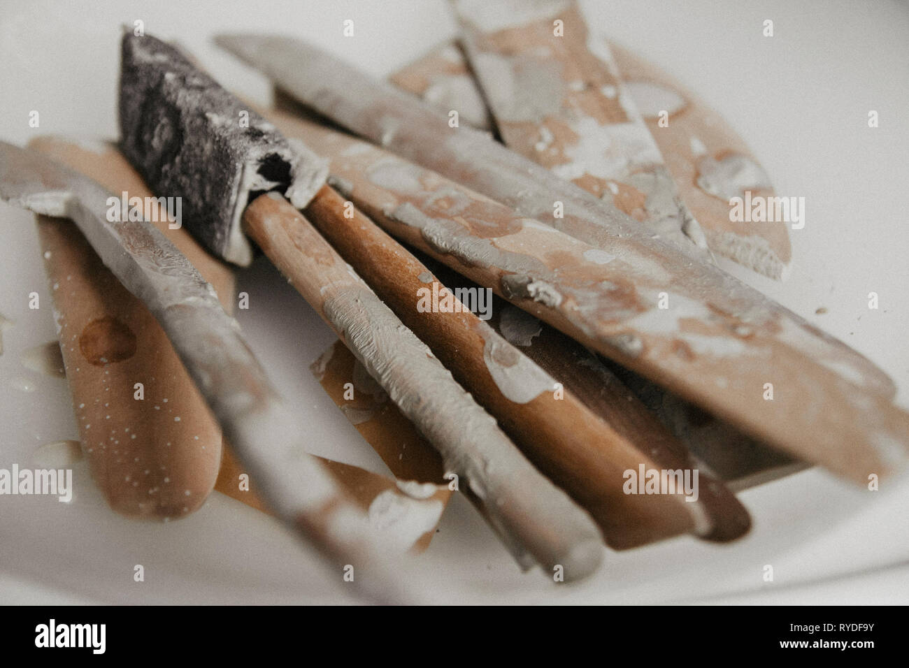 Set di sporco arte e artigianato scultura strumenti sul tavolo di legno nel laboratorio di ceramica su sfondo chiaro Foto Stock