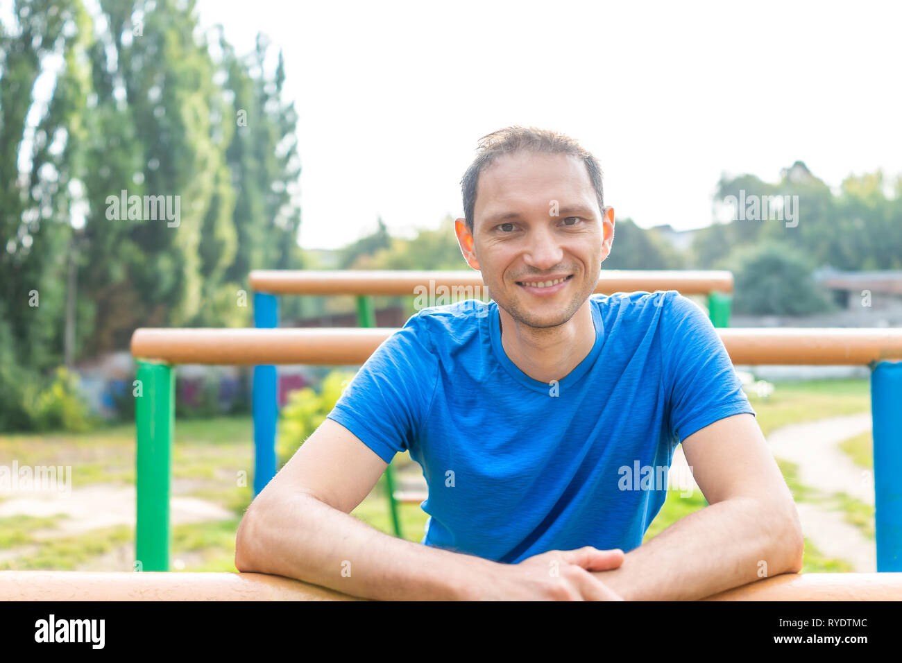Montare l'uomo muscolare closeup di faccia sorridente ritratto felice facendo allenamento calisthenics da barre orizzontali di barre parallele esercizio nel parco all'aperto in Rivne, Foto Stock