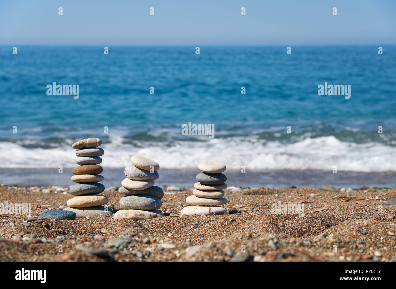 Pila di pietre di Petra tou Romiou o Aphrodite la spiaggia di roccia, Cipro. Piramide di pietre sulla spiaggia di ciottoli con mare e cielo blu su sfondo. Foto Stock