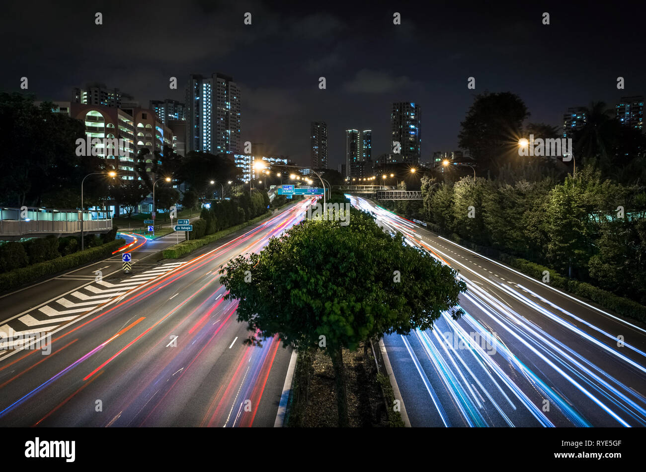 Skyline e auto faro e luce di coda percorsi su esposizione lunga strada di Singapore Foto Stock