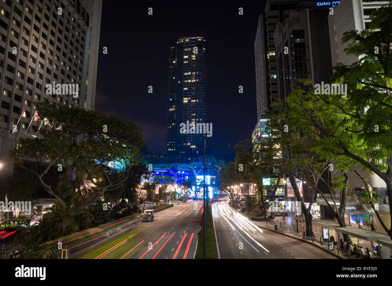 Una lunga esposizione dei fari delle automobili su Scotts Road, con grattacieli di Singapore Foto Stock