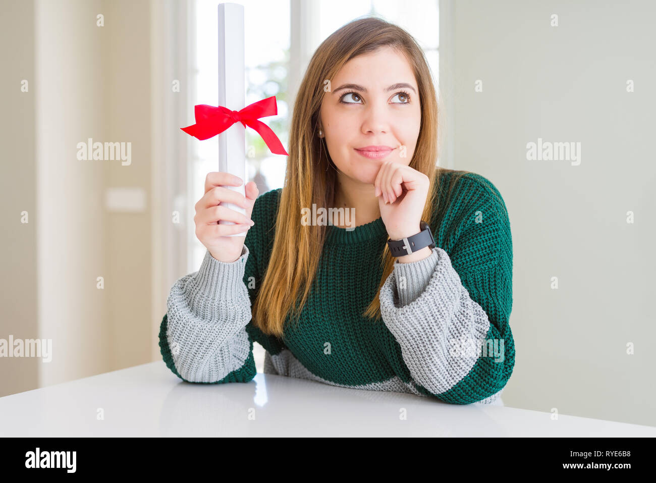 Bella giovane donna grado di contenimento con fiocco rosso faccia seriamente pensando di domanda, molto confusa idea Foto Stock