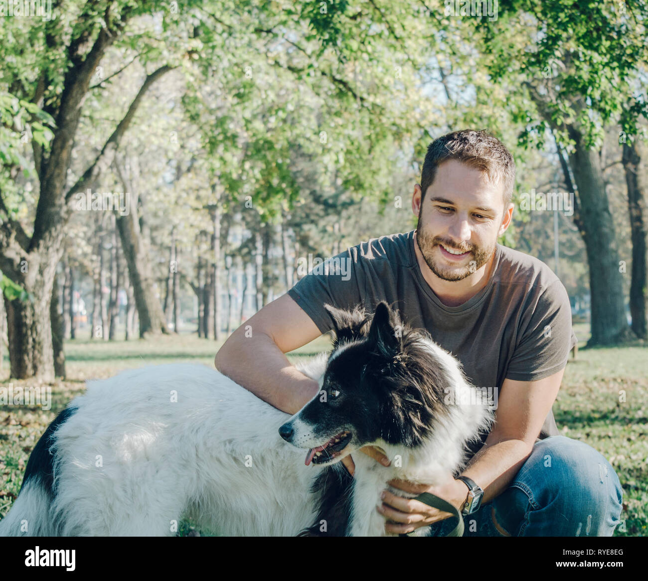L'uomo con il suo cane giocare all'aperto nel parco. Giovane proprietario avvolge il suo pet in natura. Foto Stock