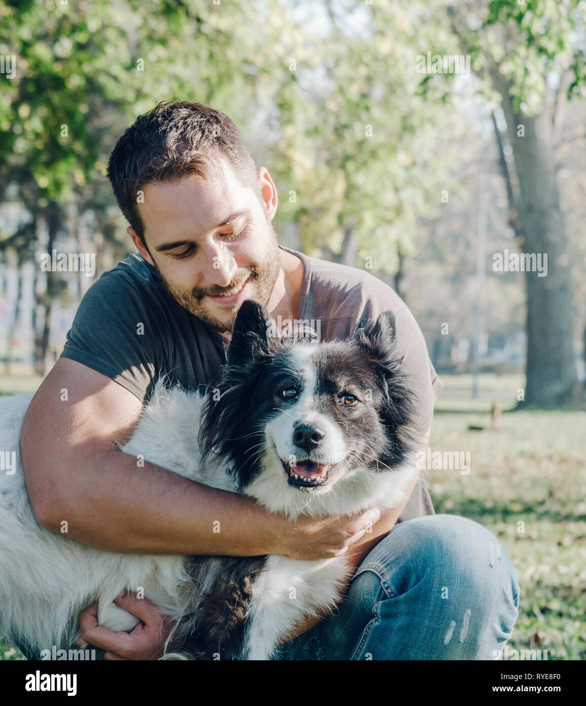 L'uomo con il suo cane giocare all'aperto nel parco. Giovane proprietario avvolge il suo pet in natura. Foto Stock