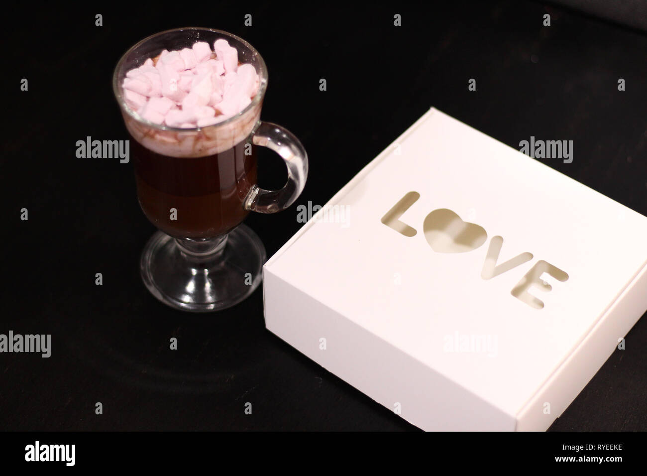 Bevanda calda in un bicchiere di vetro con rosa marshmallows Foto Stock