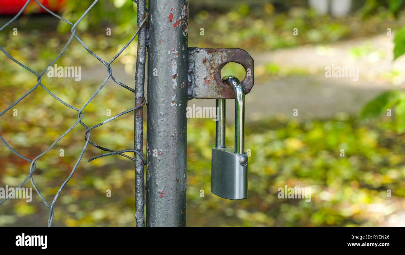 Un lucchetto Argento appeso sulla porta di casa con gli alberi sul cortile Foto Stock