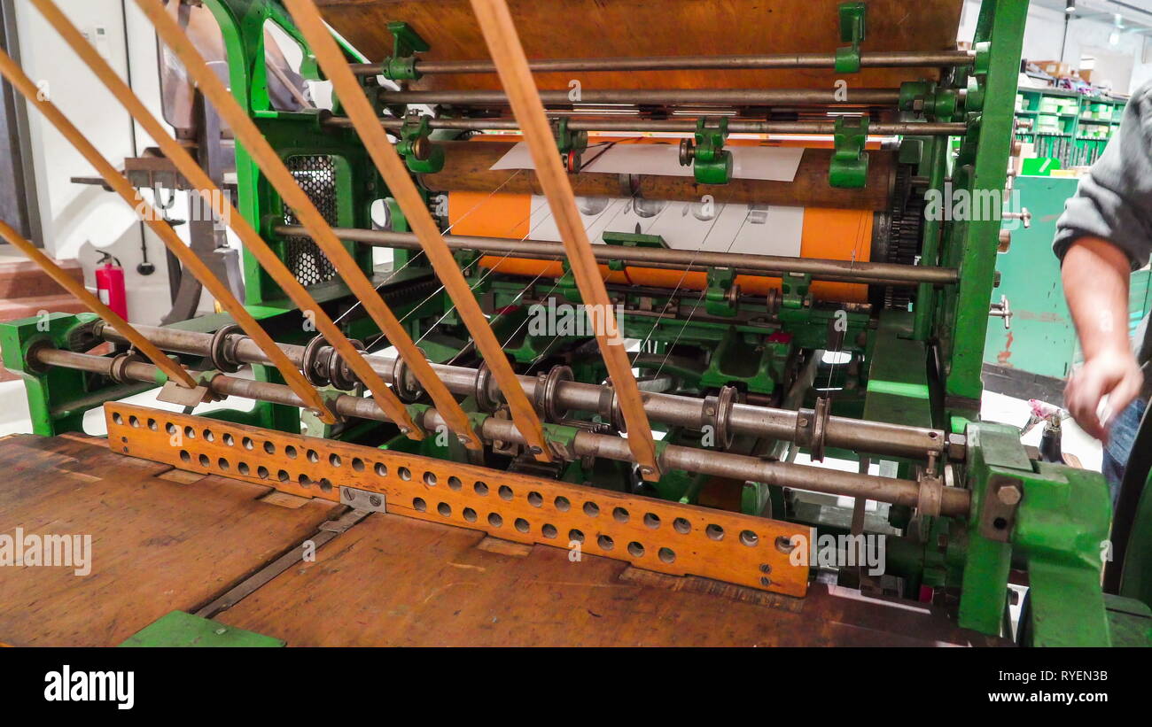 Il grande vecchio manuale macchina di stampa all'interno della fabbrica essendo azionato dal lavoratore all'interno Foto Stock