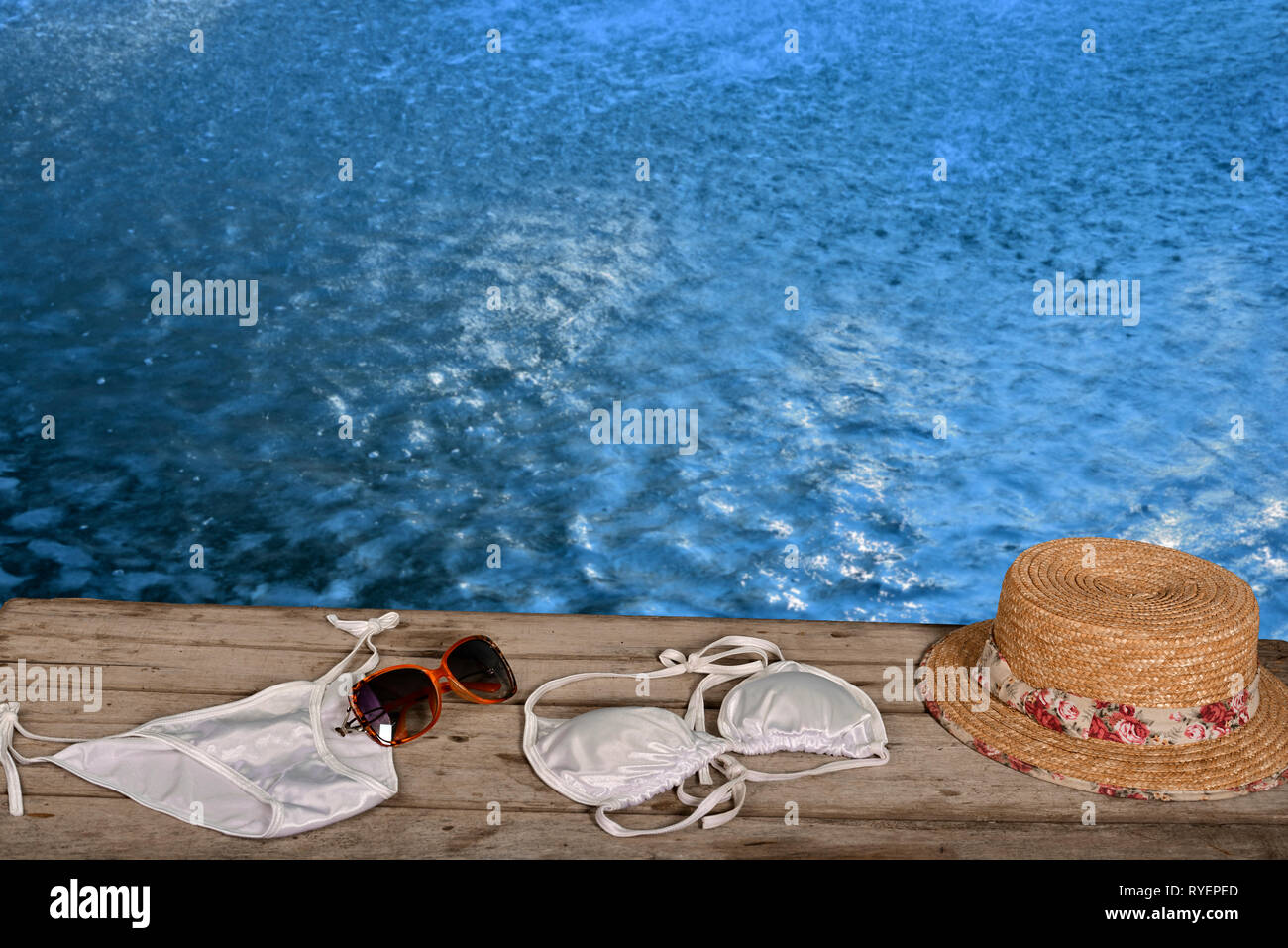 Donna sinistra asciugamano e bikini su pavimento in legno in piscina piscina Foto Stock