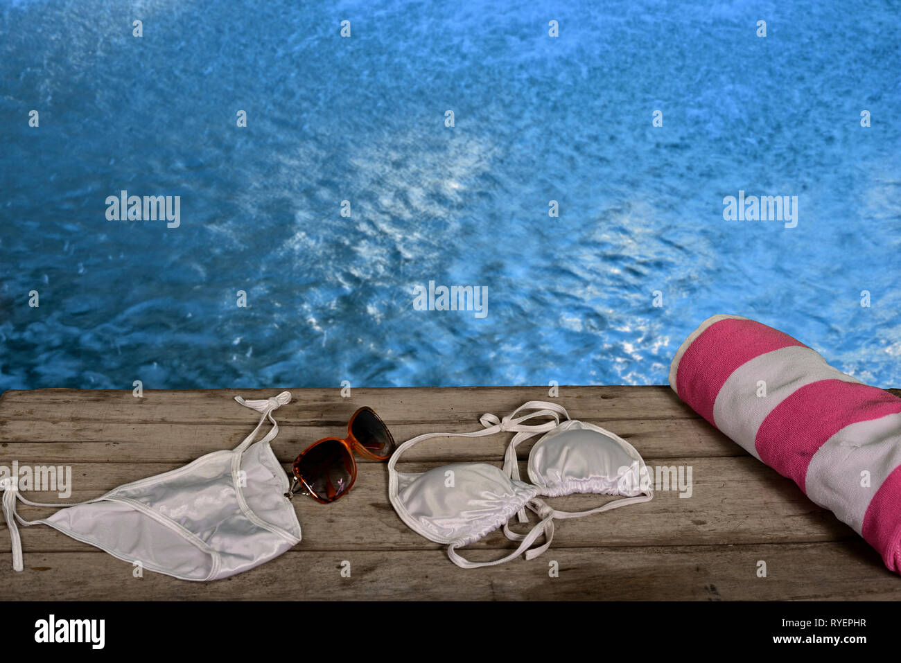 Donna sinistra asciugamano e bikini su pavimento in legno in piscina piscina Foto Stock