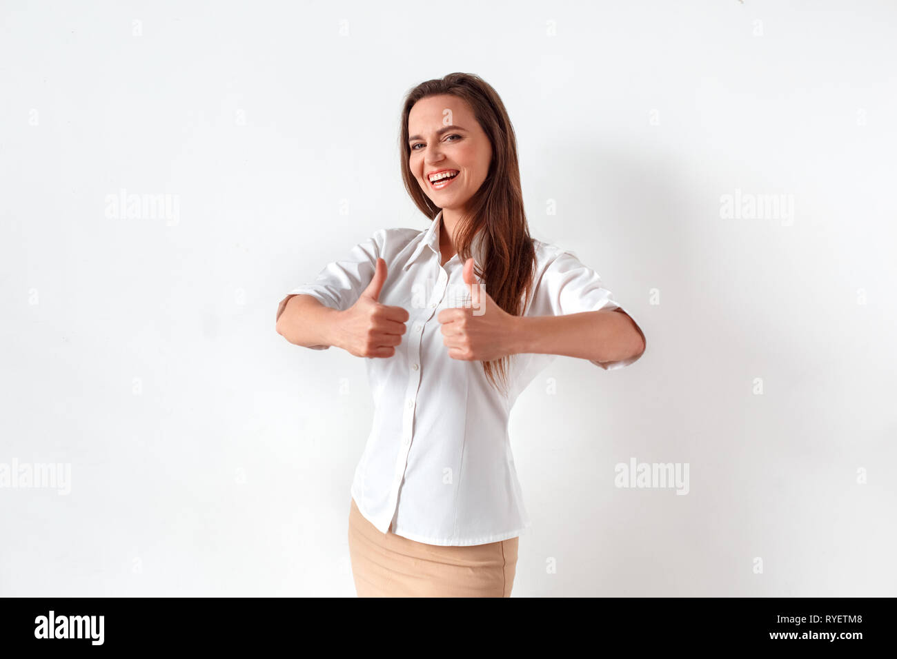 Freestyle. Donna in piedi isolato su bianco che mostra i pollici fino a ridere allegro Foto Stock