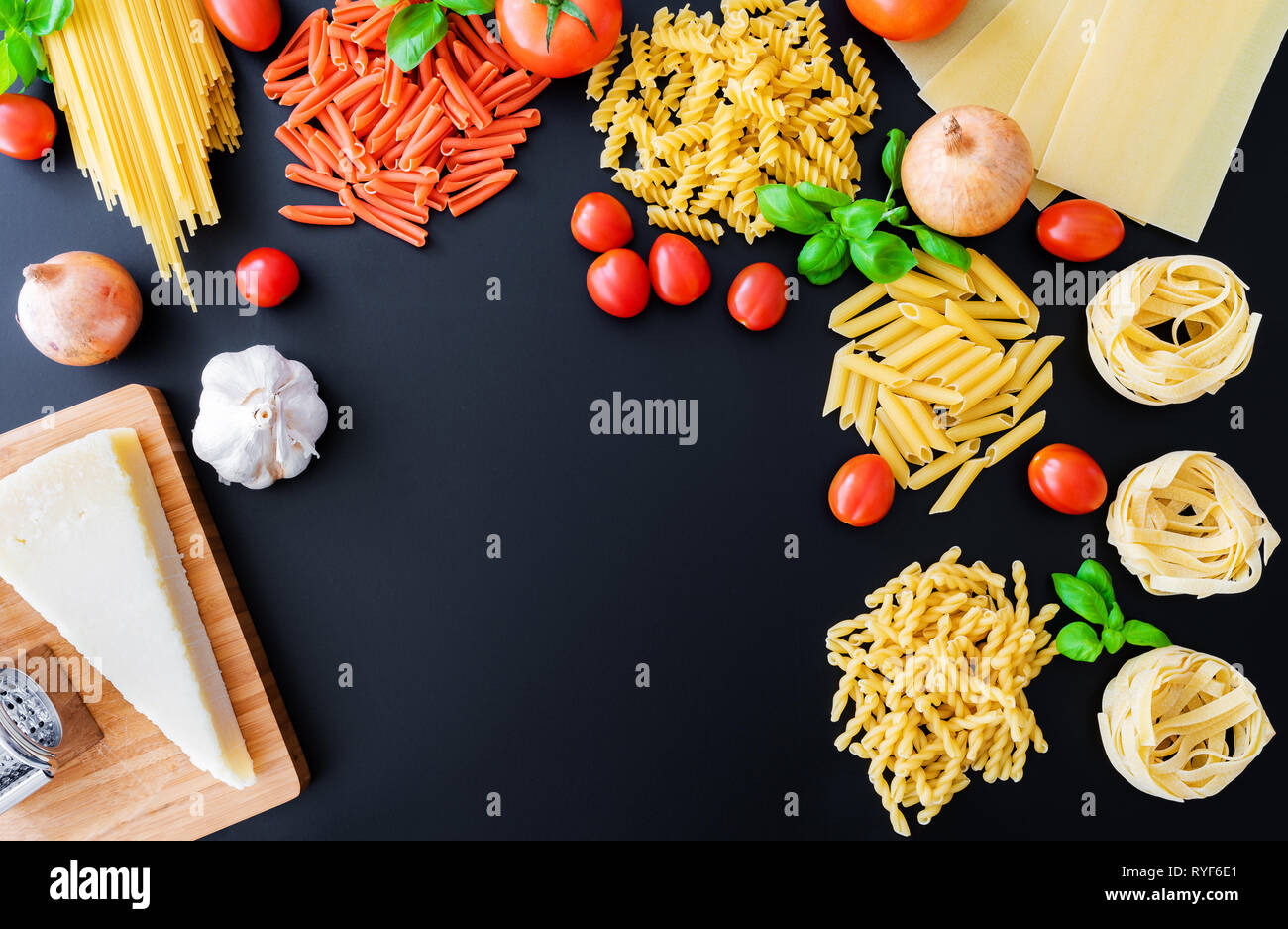 Diversi piatti di pasta italiana tagliatelle su sfondo scuro con foglie di basilico e pomodori freschi, cipolle, formaggio parmigiano e grattugia Foto Stock