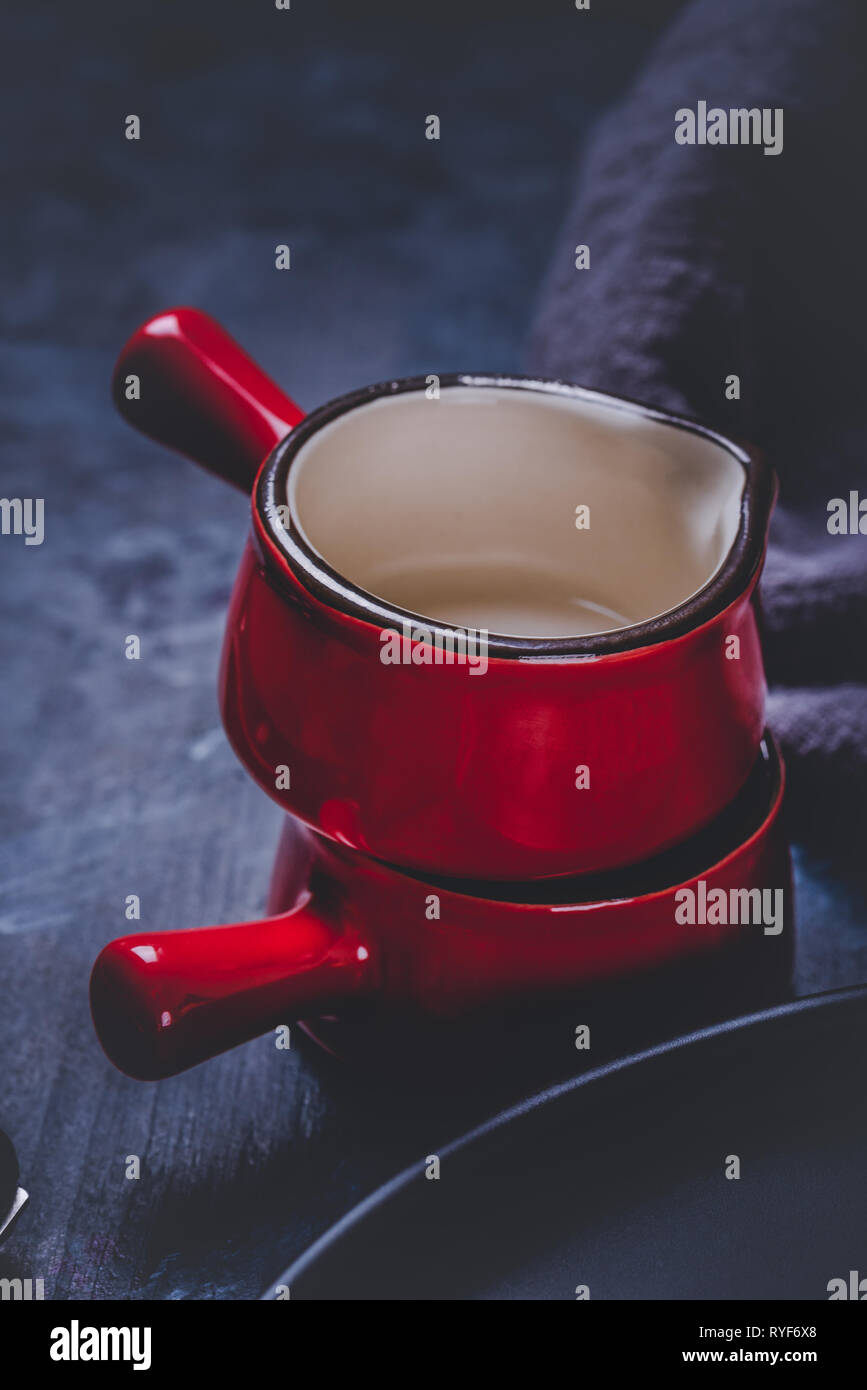 Foto verticale con due tazze. Coppe o piccole ciotole hanno saturato il colore rosso, bordo nero e bianco sul lato interno. Le tazze sono impilati e disposti su woode scuro Foto Stock