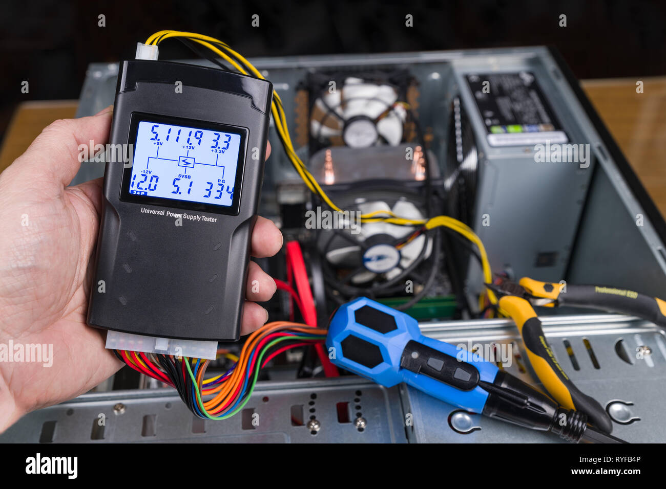 Tester per mano di unità di alimentazione. Aprire il case del computer. Digitale strumento di misurazione, connettore cavi colorati. Una pinza e un cacciavite. PC hardware manutenzione. Foto Stock