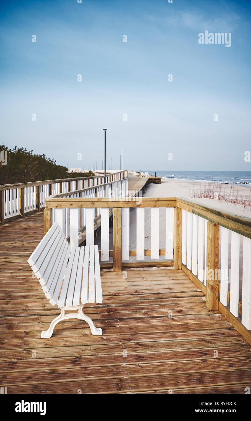 Banco vuoto su una passerella di legno da una spiaggia. Foto Stock