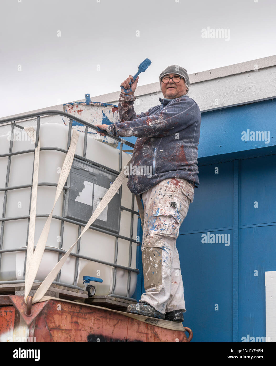 Uomo di verniciatura di un edificio, Qaqortoq, Groenlandia meridionale Foto Stock