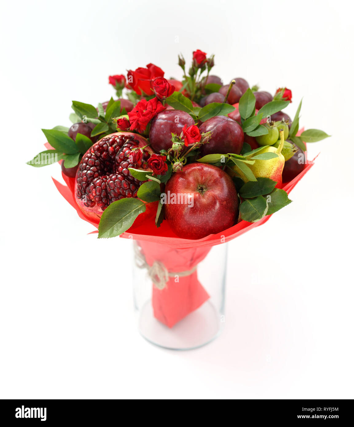 Bel bouquet consistente di melograno, mele, susine e scarlet rose in piedi in un vaso su una tavola di legno Foto Stock